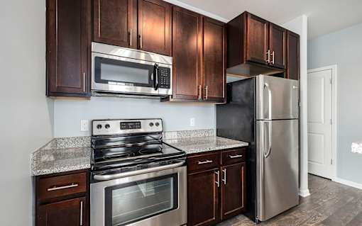 A kitchen with a stove, microwave, and refrigerator.