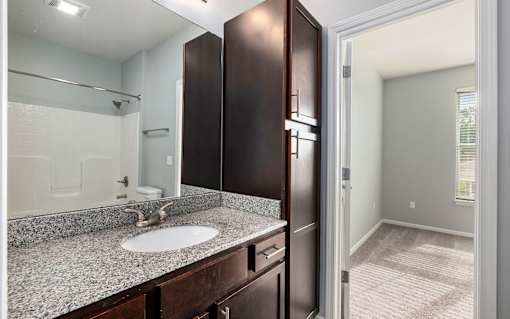 A bathroom with a sink, mirror, and cabinets.