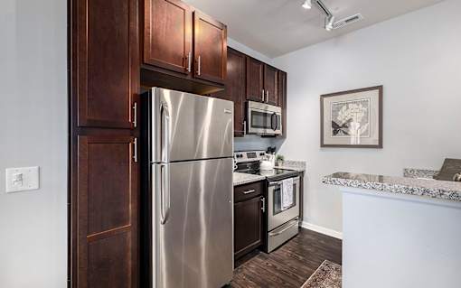 A kitchen with a refrigerator, microwave, and oven.
