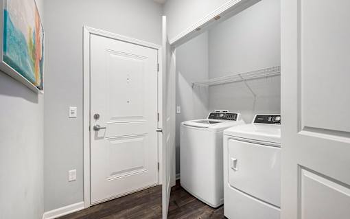 A white door is open to a laundry room with a washer and dryer.