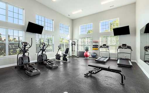 A spacious home gym with treadmills, elliptical machines, and a weight bench.
