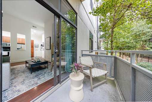 A balcony with a chair and table overlooking a tree.