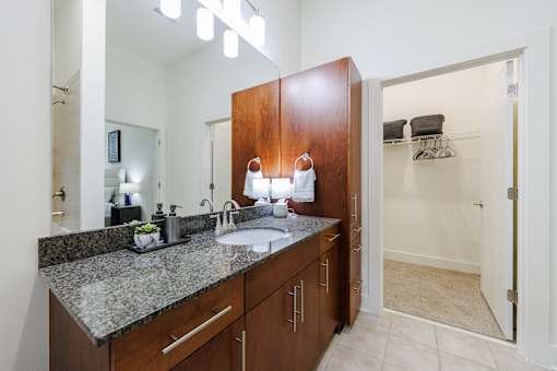 A bathroom with a sink, mirror, and wooden cabinets.