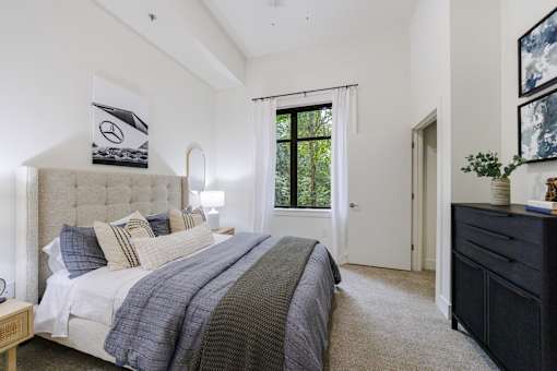 A bedroom with a large bed and a window with a view of trees.
