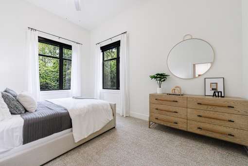 A bedroom with a bed, dresser, and mirror.
