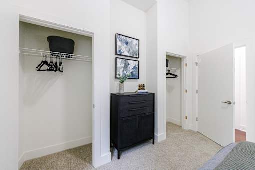 A black dresser with a hat on top is in a white room.