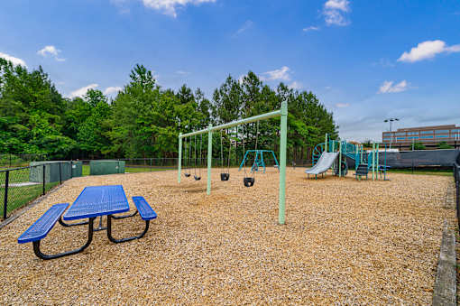 A playground with a blue picnic table and a green swing set.
