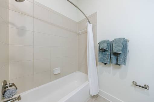 A white bathroom with a white tub and a white shower curtain.