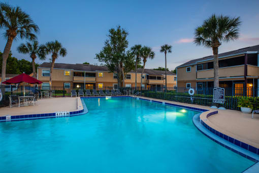 a swimming pool with palm trees and apartments in the background