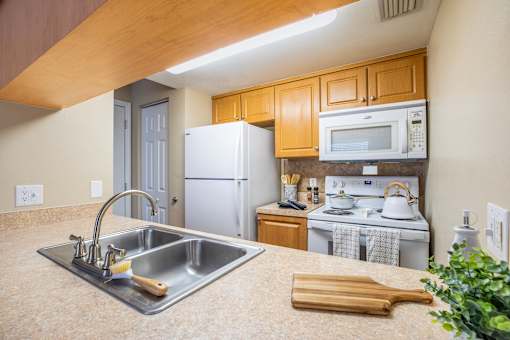 A kitchen with a stainless steel sink and a white refrigerator.