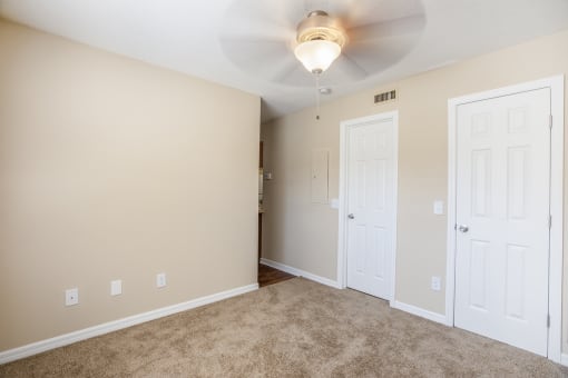 an empty living room with two doors and a ceiling fan
