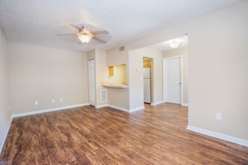 an empty living room with a ceiling fan and a bathroom