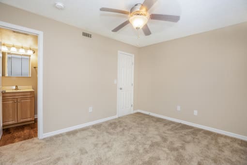 an empty living room with a ceiling fan and a bathroom