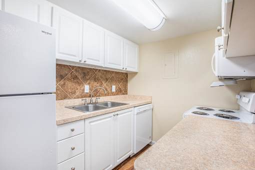 A kitchen with white cabinets and a white refrigerator.