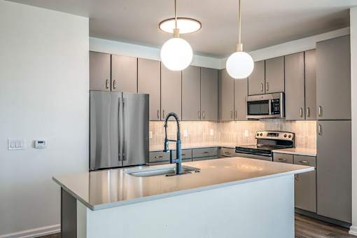 A kitchen with a refrigerator, microwave, oven, and sink.
