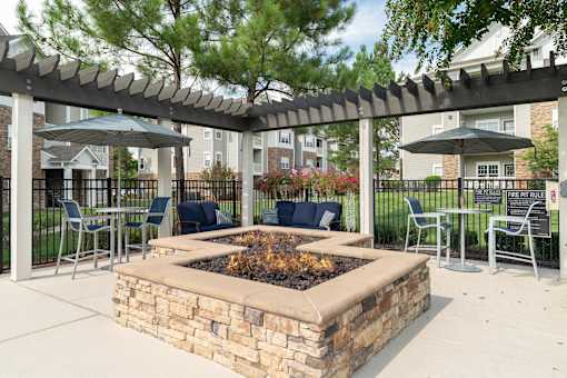 a patio with a fire pit and tables with chairs and umbrellas