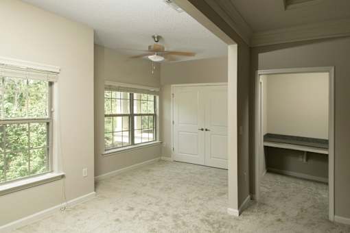 A room with a ceiling fan and a window with a view of trees.