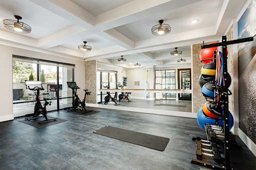 A spacious gym with exercise equipment and a mirrored wall.