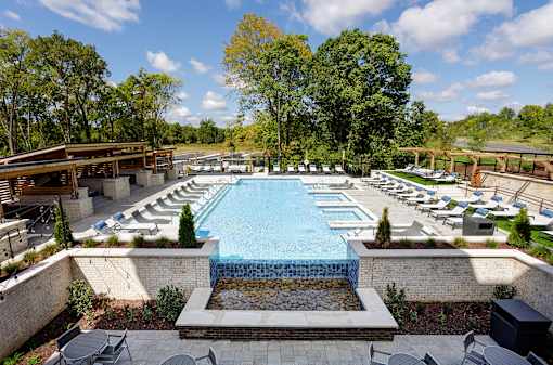 A large outdoor swimming pool surrounded by trees and lounge chairs.