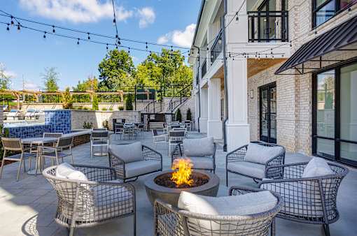 A patio with a fire pit and chairs.