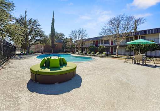 A round green and white hot tub sits in the middle of a concrete courtyard.