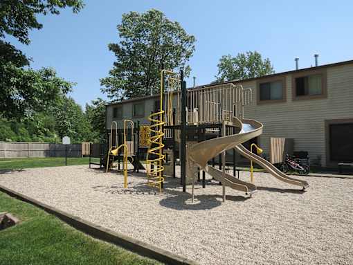A playground with a yellow slide and a yellow and black climbing structure.