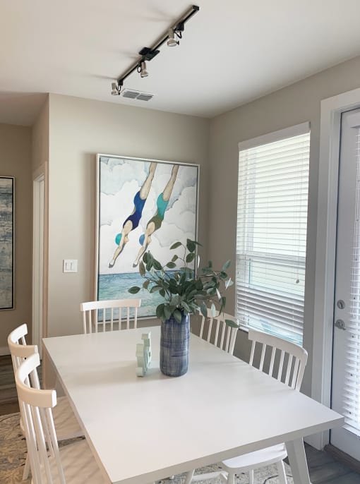 a dining room with a table and chairs and a painting on the wall