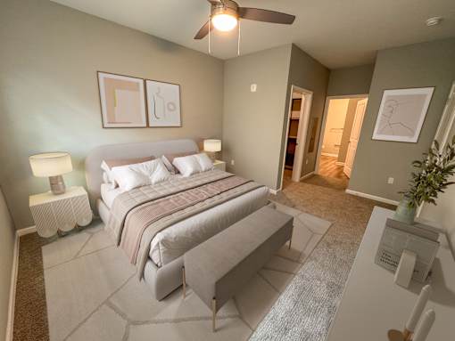 A bedroom with a bed, nightstand, and a plant.