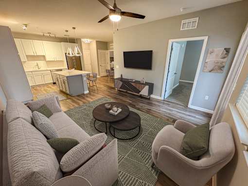 A living room with a grey couch and a green pillow.
