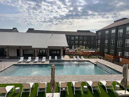 an outdoor pool with chairs and a building
