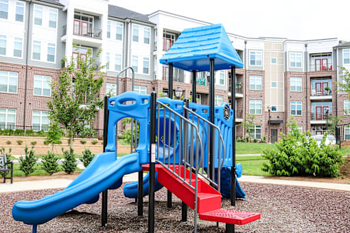 A blue and red slide in a playground with a blue roof.