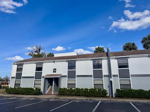 A grey building with a white door and windows.