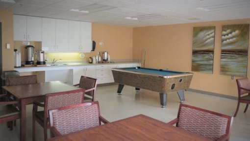 a room with a pool table and a kitchen