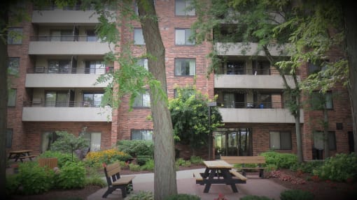 a courtyard with a picnic table and benches in front of an apartment building