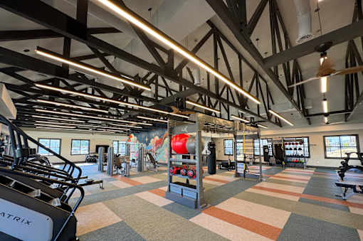 A gym with a variety of equipment including treadmills, weights, and exercise machines.
