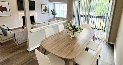 A dining room with a wooden table and white chairs.