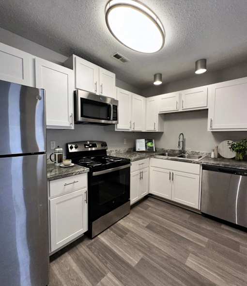 Apartments in Charlotte, NC, with In-Unit Washer and Dryer - Coffey Creek - A Modern Kitchen With White Shaker Cabinets, Stainless Steel Refrigerator, Electric Range, And A Double Sink.