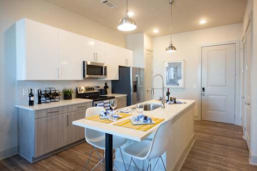 a kitchen with an island and a table with white chairs