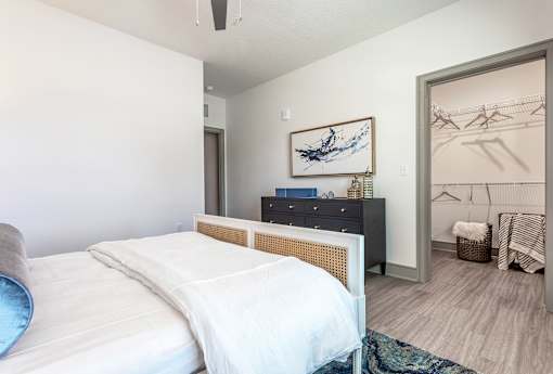 A bedroom with a bed, dresser, and painting.