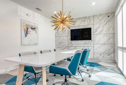 A modern conference room with a white table and blue chairs.