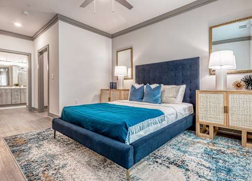 A bedroom with a large bed and a rug on the floor.
