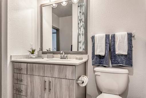 A bathroom with a white toilet and a mirror above a sink.