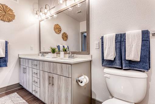 A bathroom with a white toilet and a white sink with a mirror above it.