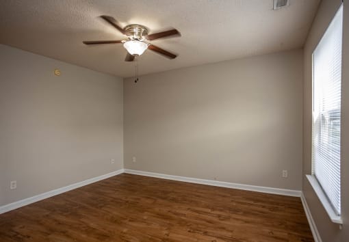 an empty room with a ceiling fan and a large window