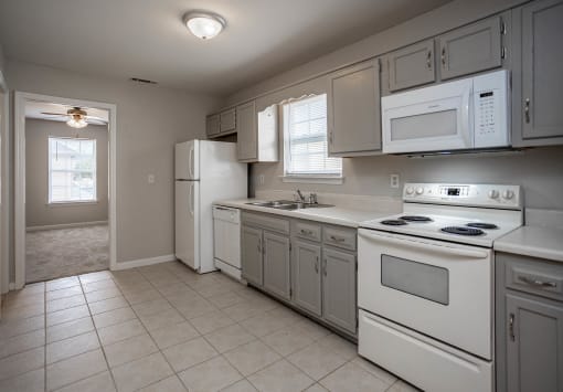 a kitchen with white appliances and white tile flooring