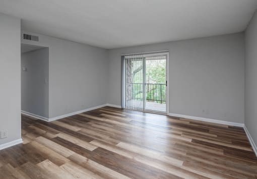 a bedroom with hardwood floors and a sliding glass door to a balcony