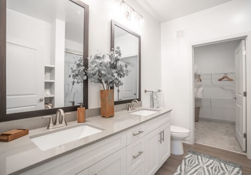 a white bathroom with two sinks and a mirror