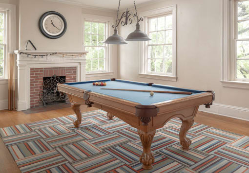 a pool table in a room with a fireplace and a clock on the wall