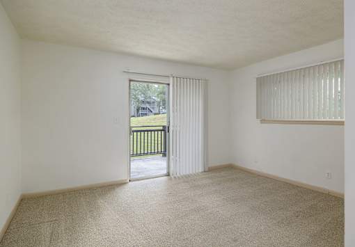 Empty room with carpeted floor and sliding glass door.