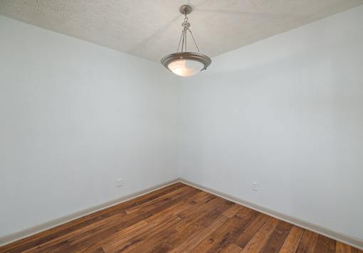 A room with wooden flooring and a hanging light fixture.